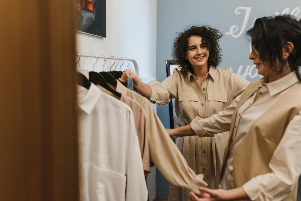 Two women enjoying a shopping experience in a modern fashion boutique, laughing and smiling.