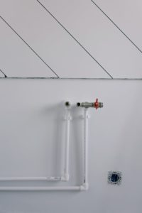 White wall with minimalist plumbing pipes and diagonal lines